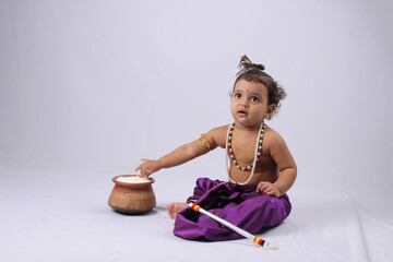 adorable Indian baby in krishna kanha or kanhaiya dress posing with his flute and dahi handi (pot...