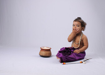adorable Indian baby in krishna kanha or kanhaiya dress posing with his flute and dahi handi (pot...