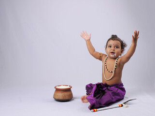 adorable Indian baby in krishna kanha or kanhaiya dress posing with his flute and dahi handi (pot...