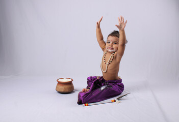 adorable Indian baby in krishna kanha or kanhaiya dress posing with his flute and dahi handi (pot...
