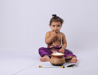 adorable Indian baby in krishna kanha or kanhaiya dress posing with his flute and dahi handi (pot...