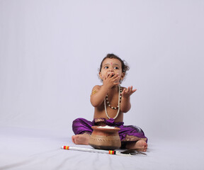 adorable Indian baby in krishna kanha or kanhaiya dress posing with his flute and dahi handi (pot...