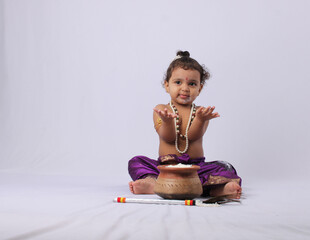adorable Indian baby in krishna kanha or kanhaiya dress posing with his flute and dahi handi (pot...