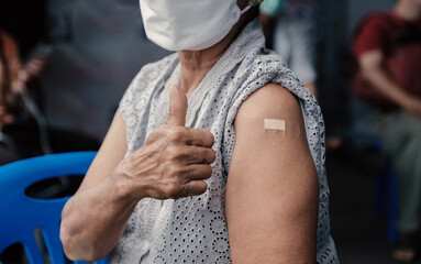 senior woman hand showing thumbs up has gone to vaccinate coronavirus covid19 shoulder with bandage...