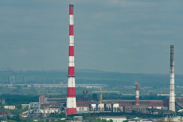 A huge red-white brick chimney in the center of an industrial city.