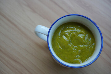 Cup filled with smoothies from green vegetables and milk                           