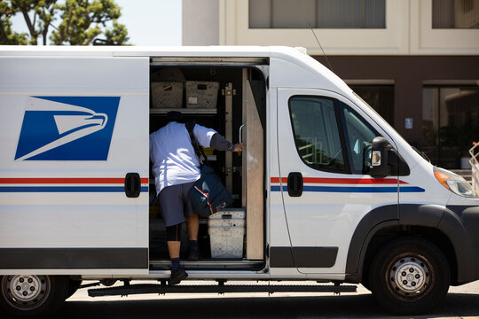 Fullerton, California, USA - July 6, 2021: A USPS Postal worker delivers mail.