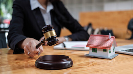 Fototapeta na wymiar Real Estate Law concept. Gavel on sounding block in hand's female judge at a courtroom, working for the insurance compensations. report the case on table
