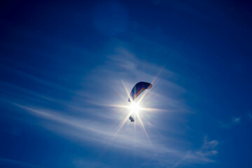 parachuter flying close to the sun, creating pilot and passenger silhouette
