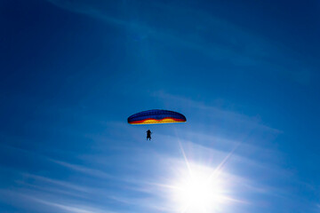 parachuter flying close to the sun, creating pilot and passenger silhouette