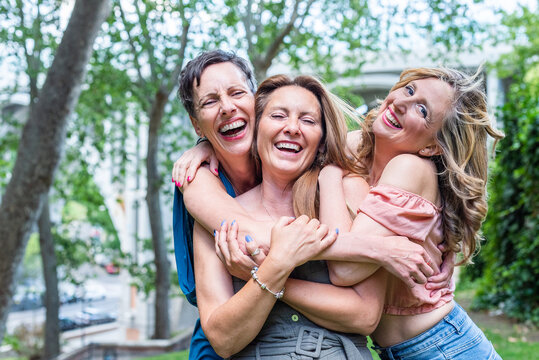 Close up of three cheerful mature female friends hugging together