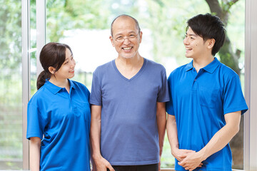 笑顔で立つ介護士と高齢者