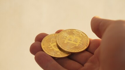 Fingers stroking golden bitcoins and then taking them away. High value of cryptocurrency at trading market. Investing into digital money for a safe and prosperous future. Digital currency in a hand.