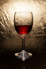Red wine in glass on a gold background.