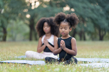 African american little girl sitting on the roll mat practicing meditate yoga in the park outdoor