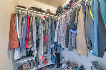 Small crowded walk in closet interior with bags and shoes