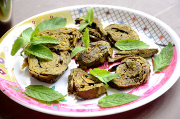 closeup the fried arabic leaves food with green mint in the plate over out of focus brown background.