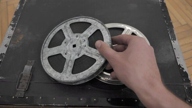 Hand Puts Old Vintage Film Reel 