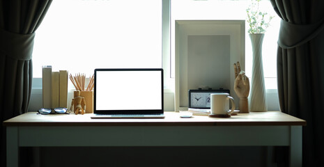 Comfortable workplace with computer laptop, picture frame and books on wooden table.