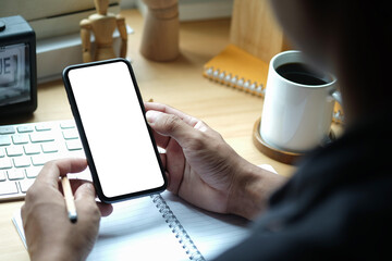 Close up over shoulder businessman using mobile phone at office desk.
