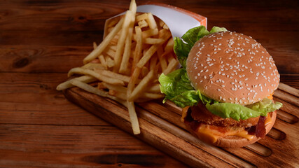Fresh tasty homemade burger and fried potatoes on wooden table.