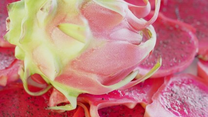 Macro close up footage of a whole dragonfruit laying on round juicy slices. Still life with dragon fruits in natural day light. Delicious dessert for tropical residents. Asian yummy fruits.