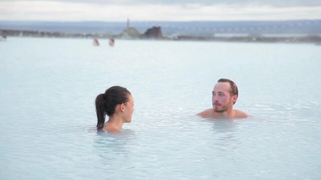 Hot spring geothermal spa on Iceland. Romantic couple in love relaxing in hot pool on Iceland. Young woman and man enjoying bathing relaxed in a blue water lagoon Icelandic tourist attraction. Sunset