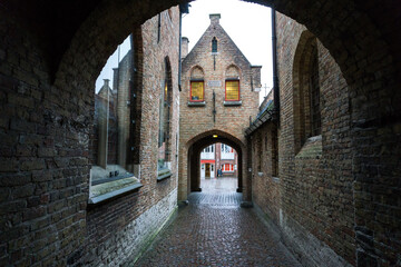 Narrow street (alley) in Bruges in a rainy day on November