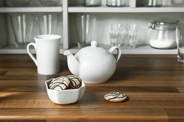 Cookies in white bowl, teapot and tea cup on the wooden table, morning and breakfast concept
