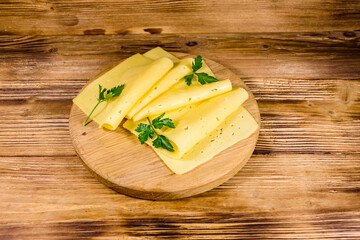 Sliced cheese and parsley on a wooden cutting board