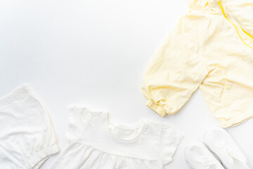 White and yellow baby clothes on a white background with copy space