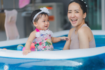 Selective focus baby girl and blur mom in swimming pool with smile happy and relax time