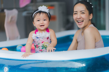 Selective focus baby girl and mom in swimming pool with smile happy and relax time