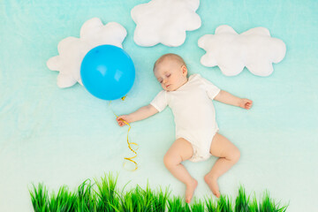 baby boy on a blue background among the clouds with a balloon sleeping