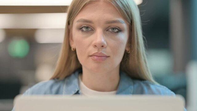 Close Up of Woman Looking at Camera while using Laptop