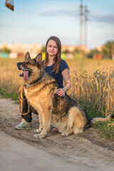 Beautiful young girl with a shepherd dog on the field.