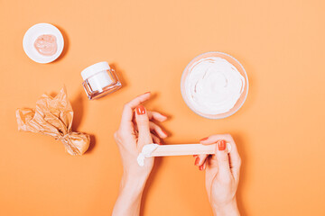 Top view of female hands applying natural clay cosmetic skin mask