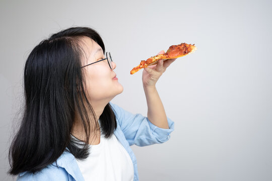 Happy glasses Asian young woman eat Pizza on white background.