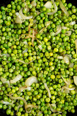 Homemade Sauteed Green Peas in a cast-iron pan, overhead view. Flat lay, top view, from above. Close-up.