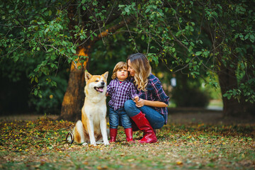 mom hugs her son near the red dog Akita inu in autumn Park