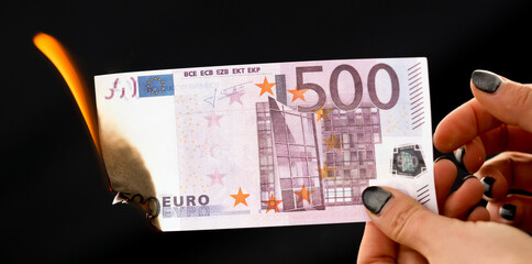 Five hundred Euros are burning with fire in hand isolated on black