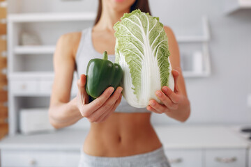 Beautiful and sporty girl in a kitchen with a vegetables