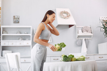 Beautiful and sporty girl in a kitchen with a vegetables