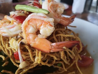 Papaya Salad with crispy rice vermicelli. There is a large shrimp.
