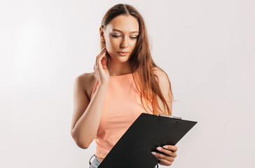 Girl student reads information in documents. Beautiful young business woman holds a clipboard with mockup on gray background. Study and business concept. Online learning