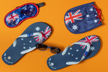 Flip flops, eye mask and sunglasses case with Australian flag on orange uniform background
