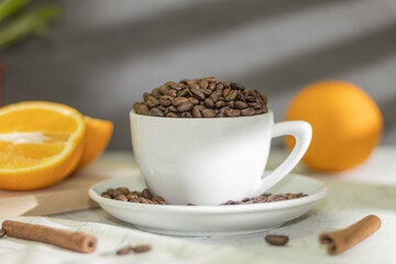 White coffee cup with coffee beans and cinnamon sticks