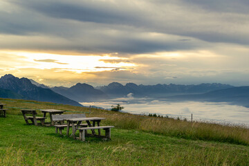 Summer mountain landscape at dawn. The valley with mountains and clouds. Picnic area on the lawn....