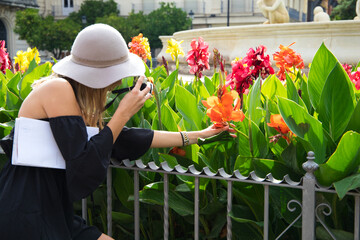 Beautiful blonde tourist with sunglasses, hat and camera taking photos on her visit to the city. Tourism, holiday and travel concept.