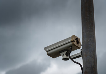 CCTV security camera in overcast dark cloudy sky.